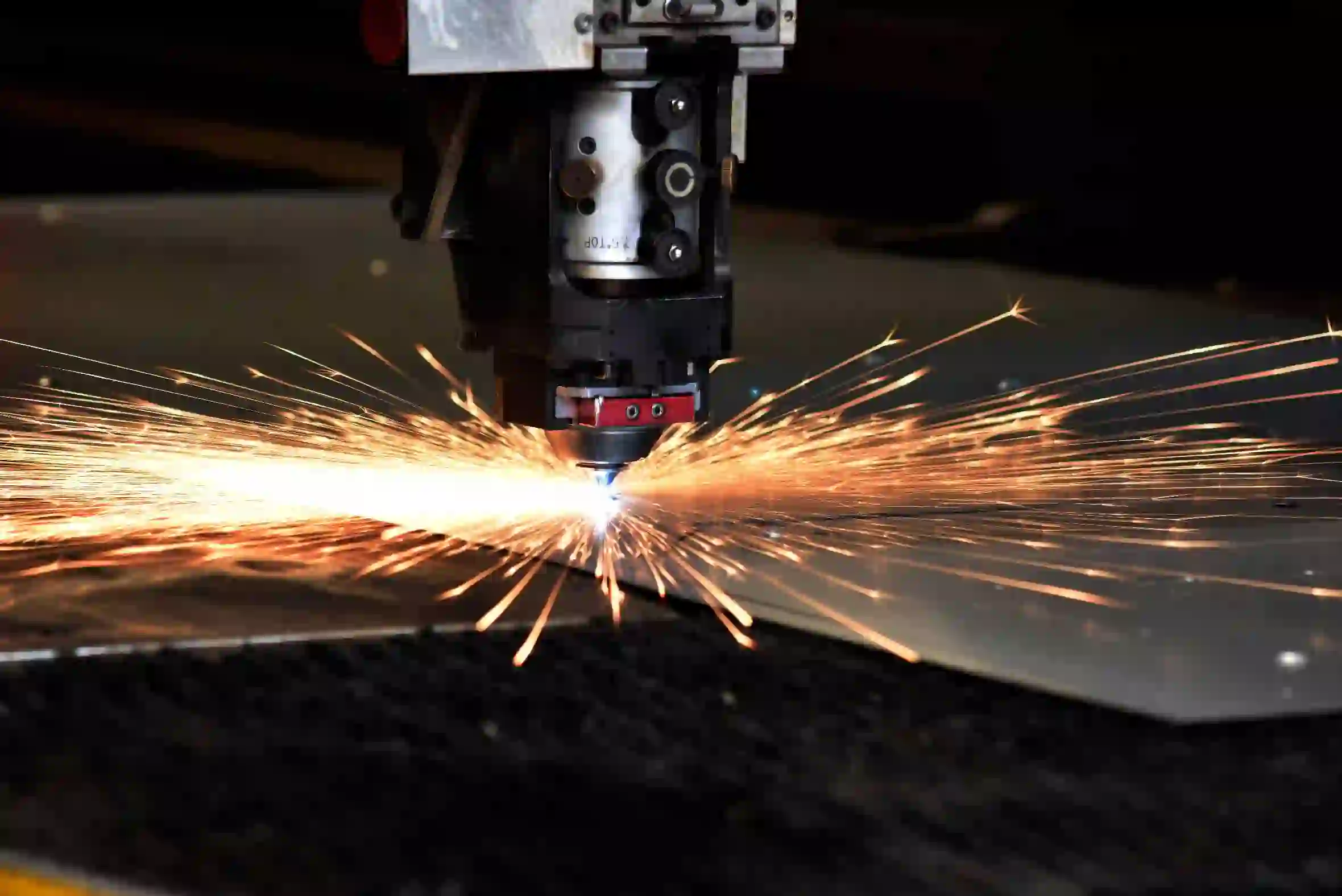 Dettaglio di un punzone laser nell'atto di tagliare una lamiera di acciaio inox, il contatto produce scintille.