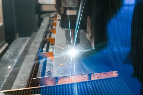 un dettaglio della macchina in opera per il taglio laser lamiera, un punzone da cui si sprigiona la luce intensissima del laser che va a contatto con il pezzo di lamiera in lavorazione