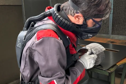 Operatore EMEL utilizza il sistema SWISS AIR durante la finitura di un componente in lamiera